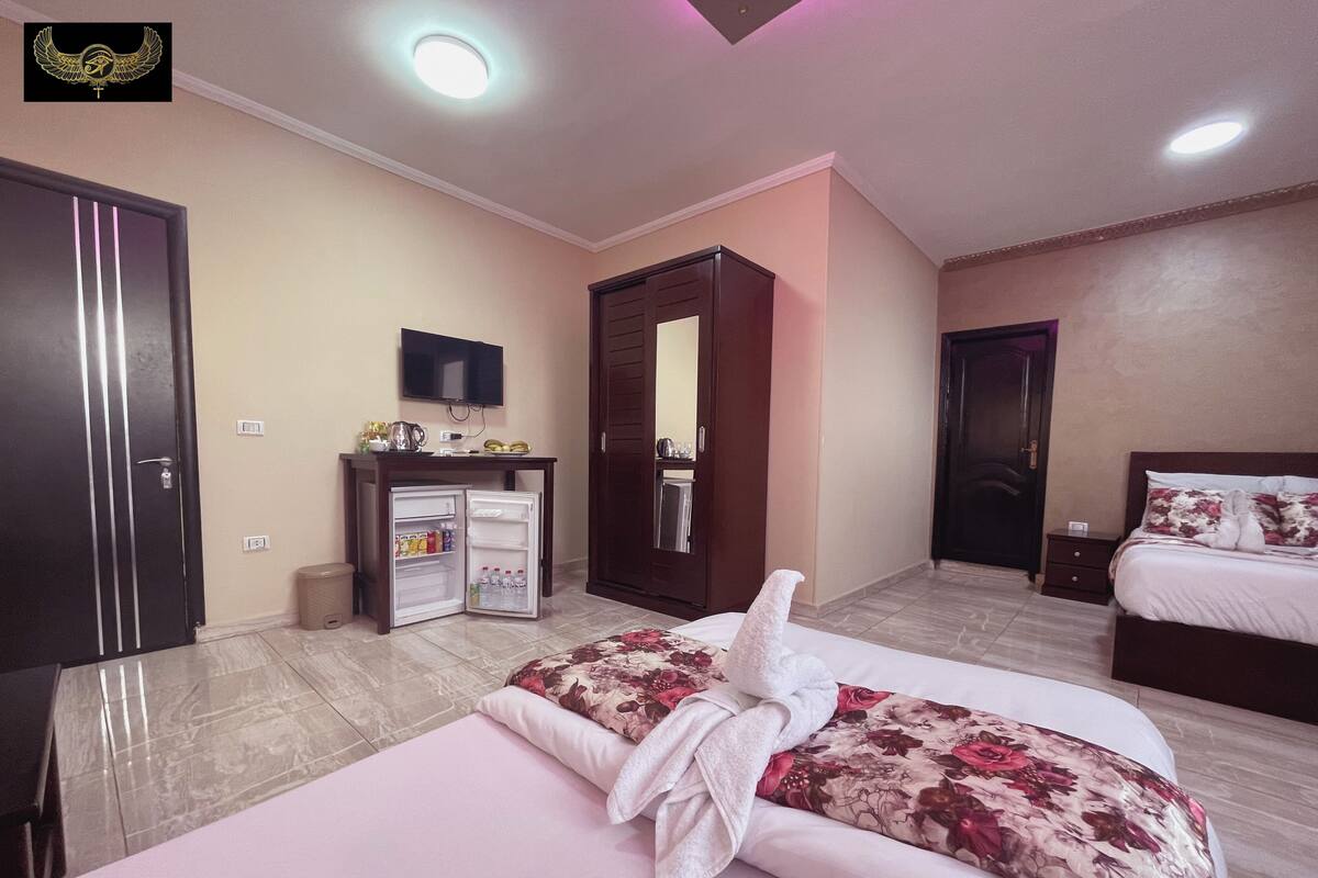 A hotel room with a bed, a small refrigerator, a television, and a wardrobe.