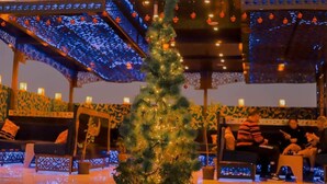 Un ambiente accogliente con un albero di Natale addobbato, zone salotto e un soffitto decorato.