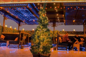 A cozy indoor setting with a decorated Christmas tree, seating areas, and a patterned ceiling.
