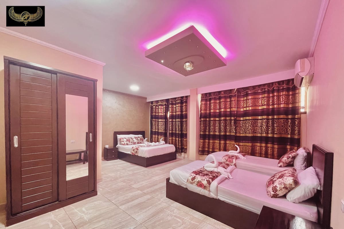 A hotel room with two beds, a wardrobe, and a ceiling light fixture.