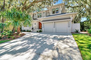 A two-story house with a garage, surrounded by lush greenery and trees. - *NEWLY BUILT HOME* 6 Bedrooms - Close to Beach - Sea Pines - Private Pool/Spa (Hilton Head Island)
