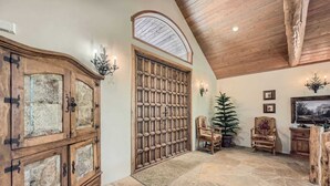 A rustic interior with a stone floor, wooden cabinets, a large wooden door, and a ceiling with exposed beams. - 5 BDR Forest Retreat w/ Hot Tub (Breckenridge)