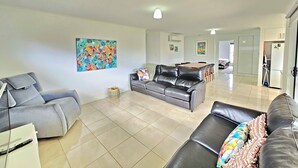 A spacious living room with a grey sofa, a black leather sofa, and a dining area with a table and chairs. - Julia's - Close to the heart of Robe (Robe)