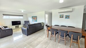 A modern living room with a TV, sofa, and dining area with chairs. - Julia's - Close to the heart of Robe (Robe)