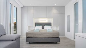 Un dormitorio moderno con una cama grande, mesitas de noche empotradas y vistas a través de puertas de cristal.