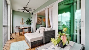 A cozy bedroom with a bed, a dining area with chairs, a ceiling fan, and a view of the outside.