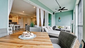 A spacious living area with a wooden dining table, wicker furniture, and a ceiling fan.
