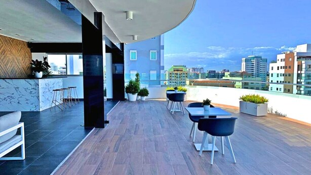 Une terrasse sur le toit dotée d’un plafond incurvé, de mobilier moderne et de plantes en pot.