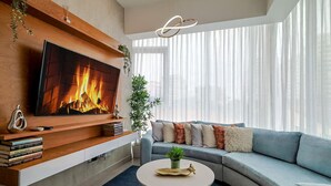 Un salon moderne avec une cheminée, un grand téléviseur à écran plat, un canapé bleu et une table basse ronde.