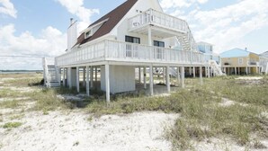 Ein Strandhaus mit Balkon, Treppe und Blick aufs Meer.