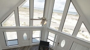Ein Zimmer mit großen Fenstern, einem Deckenventilator und Holzboden.