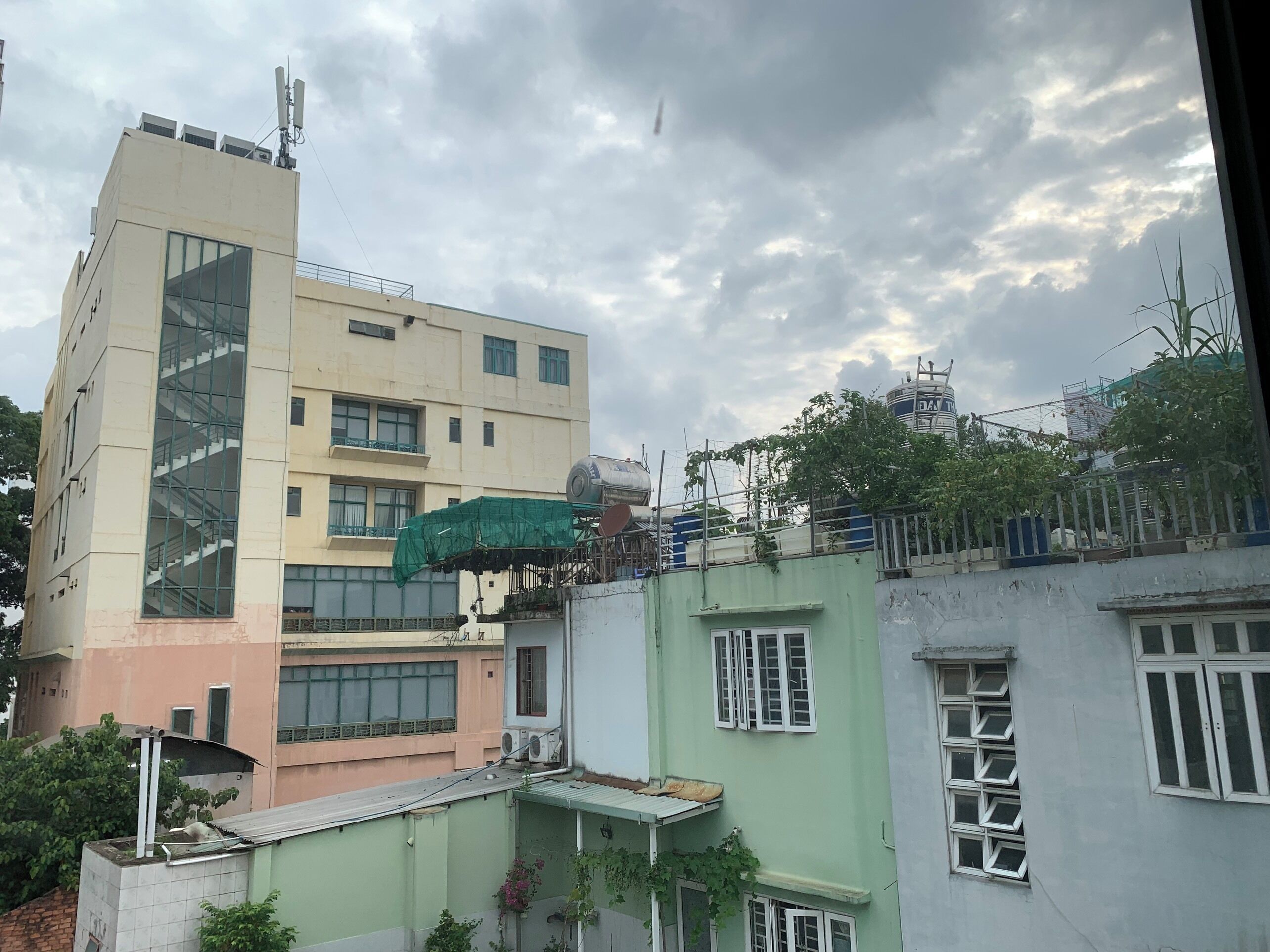 A multi-story building with a green and beige facade, large windows, and a visible staircase.