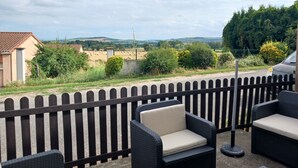 A patio area with wicker furniture and a view of the countryside.
