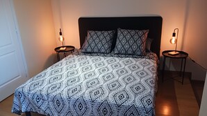 A bed with a patterned bedspread, two matching pillows, and two bedside lamps on either side.