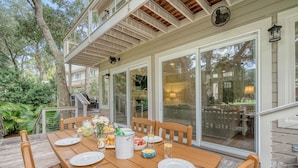 An outdoor dining area with a wooden table set for four, surrounded by chairs. - New rental, great Vanderhorst home (Kiawah Island)
