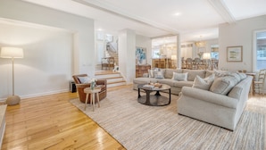 A spacious living room with a large sofa, a coffee table, and a lamp. There is a staircase leading to another level. - New rental, great Vanderhorst home (Kiawah Island)