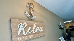 Ein hölzernes Schild mit der Aufschrift 'Relax' und 'Unwind & Enjoy' an einer Wand.
