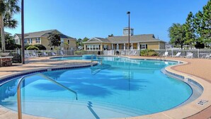 Ein Pool mit geschwungener Kante, umgeben von einem weißen Zaun und Liegestühlen.