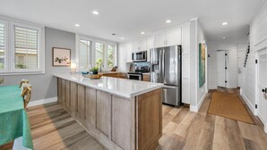 A modern kitchen with white cabinetry, stainless steel appliances, and a wooden island.