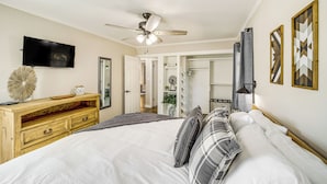 A bedroom with a bed, a ceiling fan, a TV, a dresser, and a door leading to another room. - Walk to Expo Square Pavilion: Updated Tulsa Home! (Tulsa)