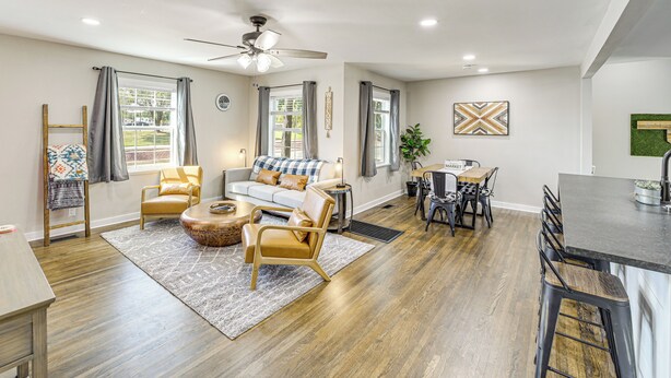 A spacious living area with a sofa, chairs, a coffee table, and a dining table with chairs. There is a kitchen area with a bar counter and stools. - Walk to Expo Square Pavilion: Updated Tulsa Home! (Tulsa)