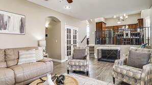 A spacious living room with a beige leather couch, patterned armchairs, and a coffee table with dumbbells. A ceiling fan and recessed lighting are visible. - El Paso Home Near Downtown & Parks (El Paso)