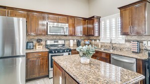 A kitchen with wooden cabinets, stainless steel appliances, granite countertops, and a central island. - El Paso Home Near Downtown & Parks (El Paso)