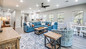 A spacious living room with a blue sofa set, a wooden coffee table, and a dining area with a white table and chairs. - Pond + Trails On-site: Washington Escape! (Washington)
