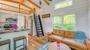 A spacious living area with a brown leather sofa, a wooden coffee table, and a kitchen with white cabinets and a microwave. - Franklin Cottage: Deck w/ Blue Ridge Mtn Views! (Franklin)