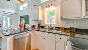 A modern kitchen with white cabinets, a granite countertop, and a built-in dishwasher. - Franklin Cottage: Deck w/ Blue Ridge Mtn Views! (Franklin)