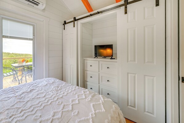 A bedroom with a bed, a TV on a dresser, and a sliding door leading to an outdoor area. - Franklin Cottage: Deck w/ Blue Ridge Mtn Views! (Franklin)