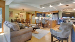 Una cocina moderna con una isla central, taburetes de bar y un comedor con mesa y sillas de madera.