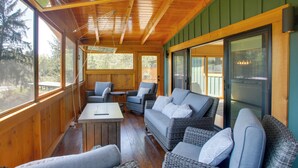 Una terraza de madera con mobiliario de mimbre, una mesa y vistas al exterior.