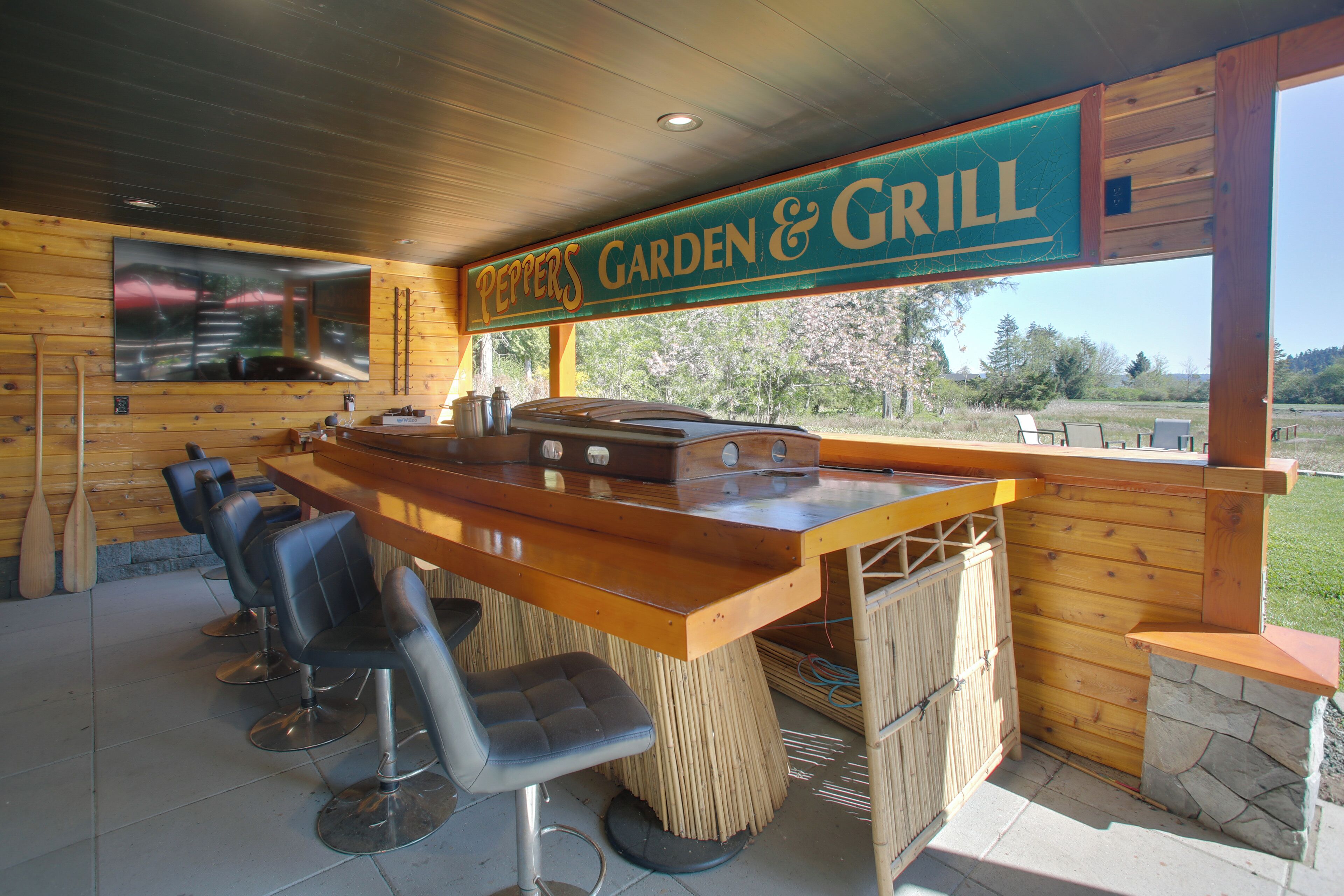 A restaurant with a bar area, wooden walls, and a view of the outdoors.