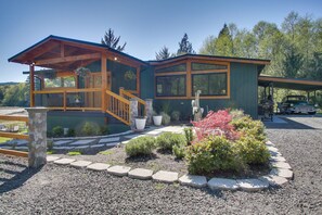 A two-story house with a wooden deck, large windows, and a stone pillar. - Puget Sound Views, 8.5 Acres! Luxury Outdoor Oasis (Port Ludlow)