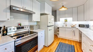 A modern kitchen with white cabinets, stainless steel appliances, and a wooden floor. - Central Boulder Home w/ Outdoor Oasis, Walk to CU! (Boulder)