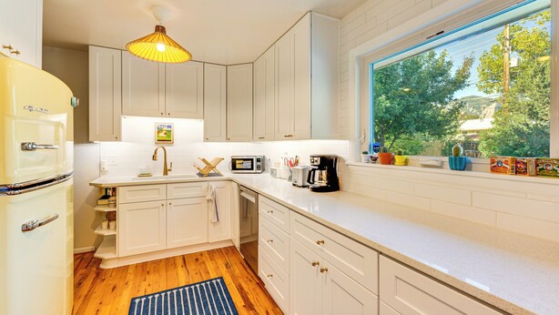 A modern kitchen with white cabinets, a built-in oven, and a window with a view of trees. - Central Boulder Home w/ Outdoor Oasis, Walk to CU! (Boulder)