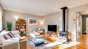 A living room with a sofa, coffee table, TV, bookshelf, and a fireplace. - Central Boulder Home w/ Outdoor Oasis, Walk to CU! (Boulder)