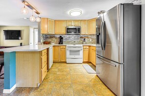 A modern kitchen with wooden cabinets, stainless steel appliances, and a tiled backsplash. - 10 Mi to Bonita Beach: Pet-friendly Home w/ Yard! (Bonita Springs)
