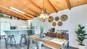 Une cuisine moderne avec un plafond en bois, un îlot central doté de tabourets et des éléments décoratifs fixés au mur.