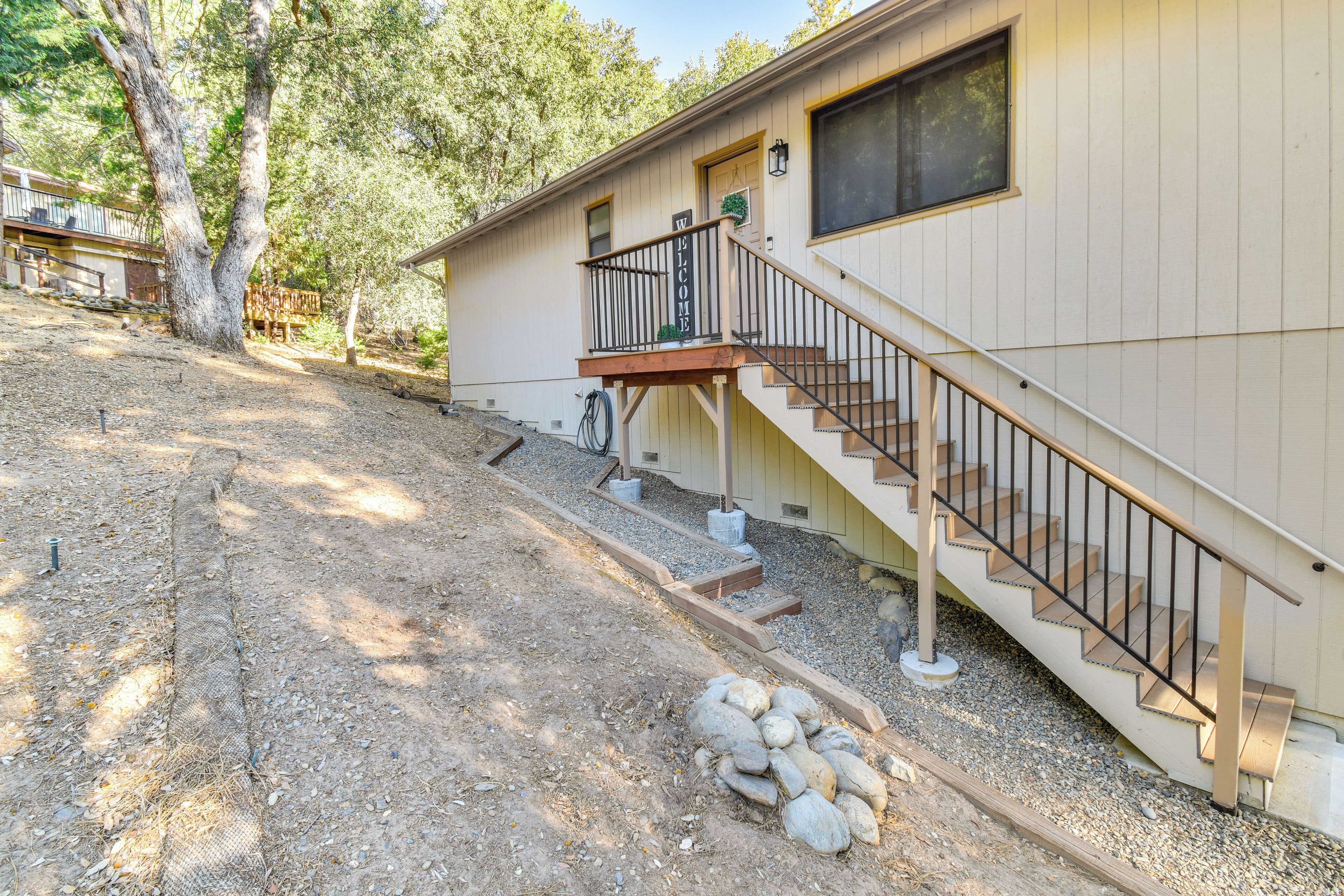 A single-story house with a wooden deck, a staircase, and a welcome sign.