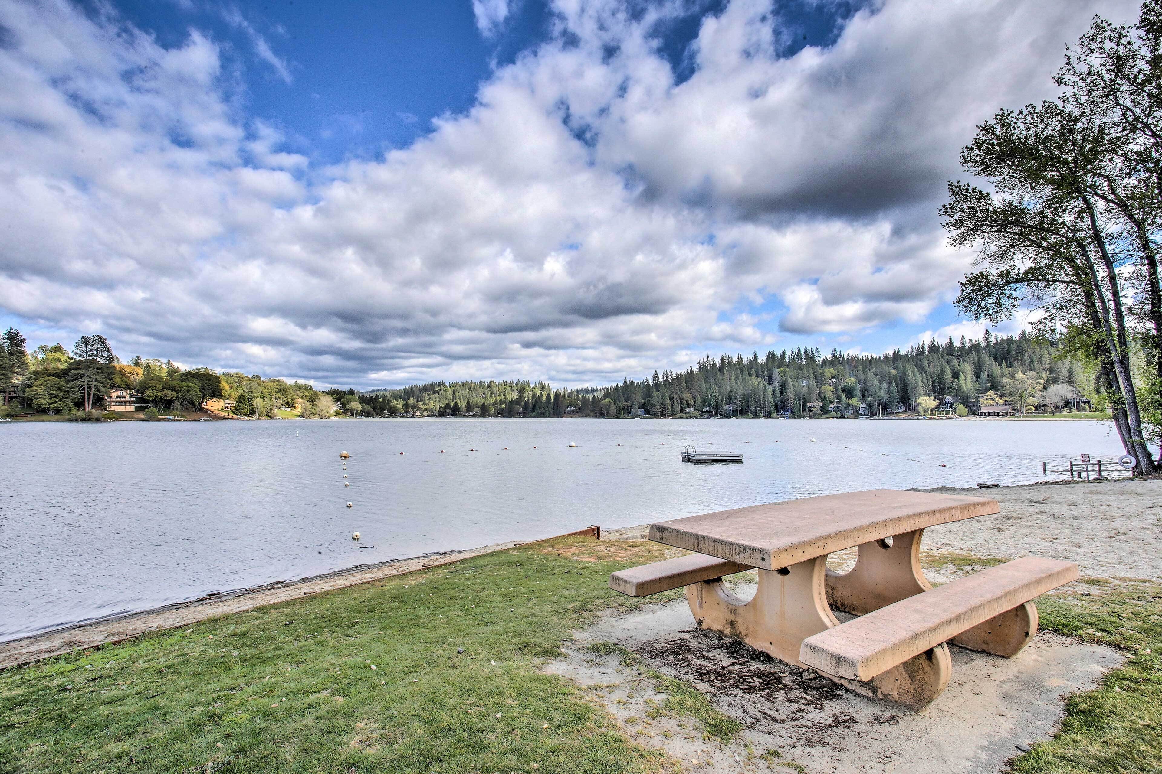 A picnic table by a lake with a dock in the background.