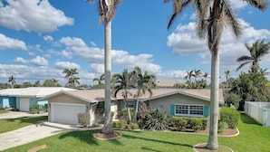 A residential area with houses, palm trees, and a clear sky. - Canal-front Home w/ Boat Lift in Cape Coral! (Cape Coral)