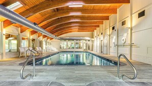 Una piscina interior con techo de madera y suelo de piedra.