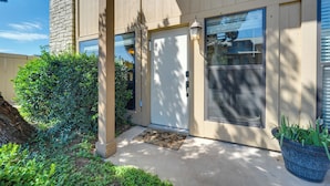 A building entrance with a door, a small step, a doormat, a potted plant, and a window with blinds. - Townhome Near Lake LBJ w/ Deck & Patio! (Horseshoe Bay)