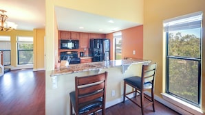 A modern kitchen with wooden cabinets, a black refrigerator, and a granite countertop. - Townhome Near Lake LBJ w/ Deck & Patio! (Horseshoe Bay)