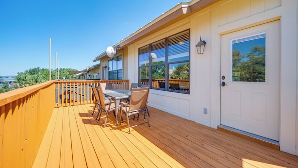 A wooden deck with a table and chairs, a white door, and windows with blinds. - Townhome Near Lake LBJ w/ Deck & Patio! (Horseshoe Bay)