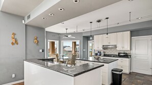 Een moderne keuken met een centraal eiland, witte kasten en een eethoek met stoelen.