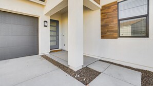 Une maison moderne avec un garage, une porte d’entrée et une fenêtre équipée de stores.
