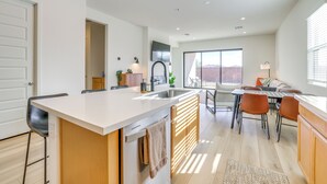 Une cuisine moderne dotée d’un îlot central, d’un coin repas avec des chaises et d’une grande fenêtre offrant une vue dégagée.